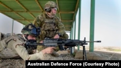 Seorang pelatih militer dari AD Australia dari Ninewa Operations Command Commando Battalion mengamati seorang serdadu AD Irak saat menggunakan senjata mesin M249 berpeluru tajam di Taji Military Complex, Iraq.