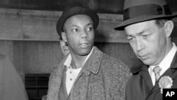 Foto Achiv: Muhammad Aziz, yon sispek nan asasina Malcolm X mache ak detektiv lapolis nan Nouyok, 26 Fev. 1965.