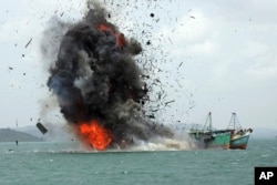FILE - In this Feb. 22, 2016, file photo, debris fly into the air as foreign fishing boats are blown up by Indonesian Navy off Batam Island, Indonesia.