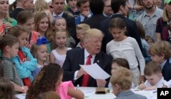 President Donald Trump shows the letter he wrote to a service member during the annual White House Easter Egg Roll on the South Lawn of the White House in Washington, April 17, 2017.