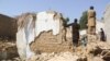 Warga berdiri di tengah puing-puing rumah yang rusak akibat gempa di Harnai, Balochistan, Pakistan, 7 Oktober 2021. (Foto: REUTERS/Naseer Ahmed)