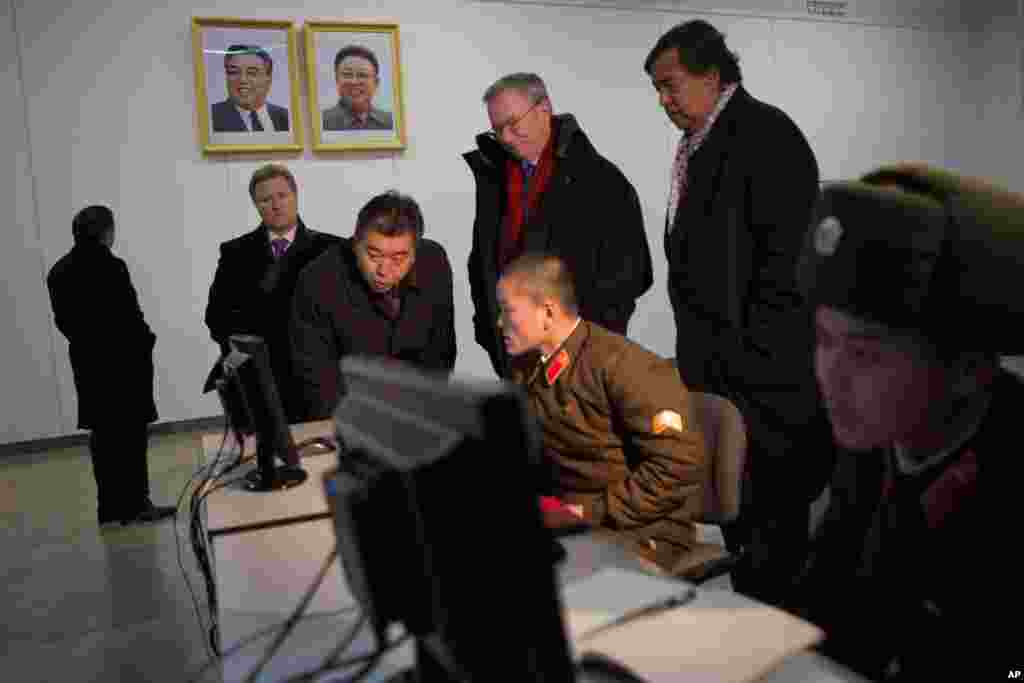 谷歌执行董事长施密特和前美国墨西哥州州长里查森2013年1月9日在平壤人民大学习堂观看士兵操作电脑。