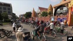 Drivers ride their three-wheeled pedicab along a street in Phnom Penh, Cambodia, Friday, March 27, 2020. (AP Photo/Heng Sinith)