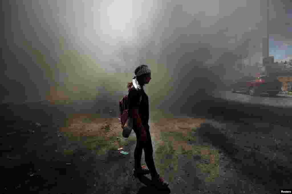 A Palestinian girl stands amongst smoke during clashes with Israeli troops at a protest near the Jewish settlement of Beit El, near Ramallah, in the occupied West Bank.