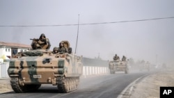 FILE - Turkish army tanks and armored personnel carriers move toward the Syrian border, in Karkamis, Turkey.