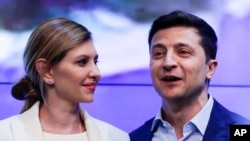 Ukrainian comedian and presidential candidate Volodymyr Zelenskiy, and his wife Olena Zelenska smile as they greet supporters at his headquarters after the second round of presidential elections in Kiev, Ukraine, Sunday, April 21, 2019. (AP Photo/Sergei G