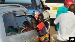 FILE - A Ugandan street child begs as traffic passes by, in Kampala, July 17, 2014.