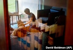 Law student Amelia Myers, 25, is reflected in a book case in the law library as she plays with Hooch, a 19-month-old golden retriever, between final exams at Emory University in Atlanta.