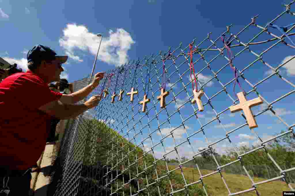 Bob Ossler, chaplain with the Cape Coral volunteer fire department, places 17 crosses for the victims of Wednesday's shooting at Marjory Stoneman Douglas High School on a fence a short distance from the school in Parkland, Florida, Feb. 15, 2018. 
