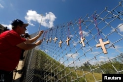 Bob Ossler, chaplain with the Cape Coral volunteer fire department, places 17 crosses for the victims of Wednesday's shooting at Marjory Stoneman Douglas High School on a fence a short distance from the school in Parkland, Florida, Feb. 15, 2018.