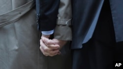Mark Phariss (L) clutches the hand of partner Victor Holmes as they talk to the media outside the U.S. Federal Courthouse in San Antonio, Texas, Feb. 12, 2014.