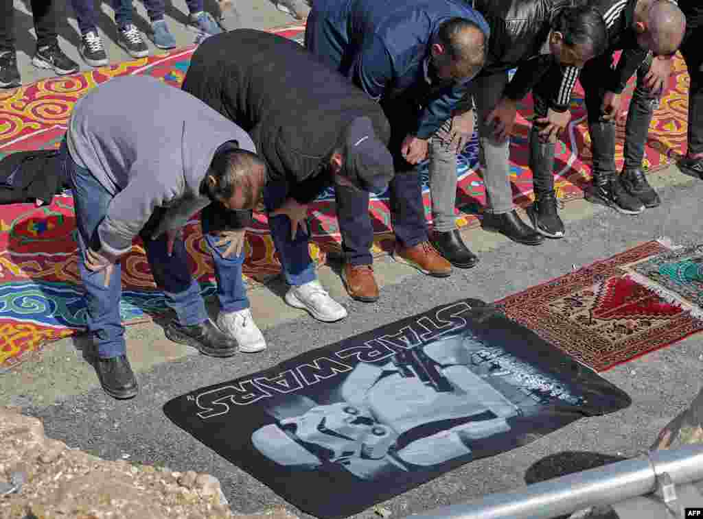 Palestinian Muslim men perform the Friday noon prayer in a street in Jerusalem&#39;s east neighborhood of Sheikh Jarrah.