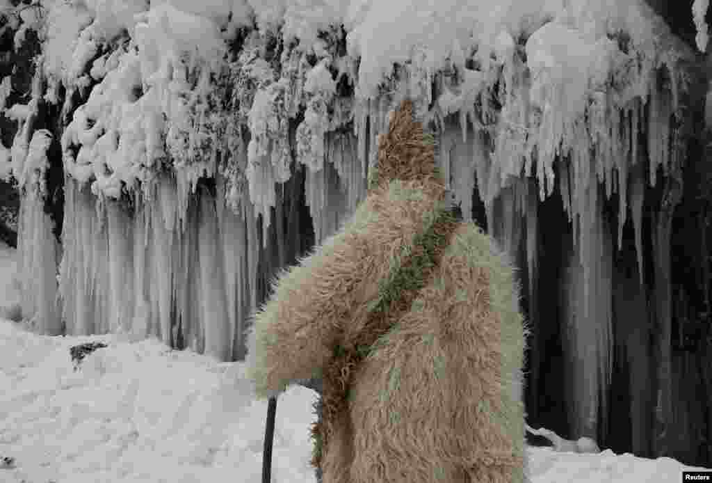 A man passes by a frozen waterfall in the village of Jezerc, Kosovo.