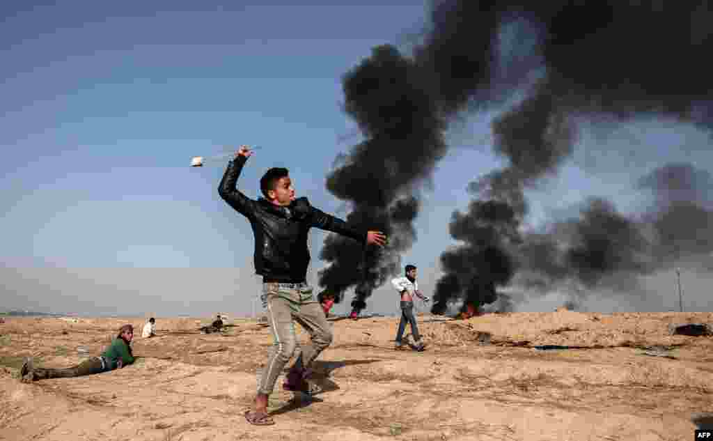 A Palestinian demonstrator swings a slingshot during clashes with Israeli forces near the border with Israel in the southern Gaza strip city of Khan Yunis.