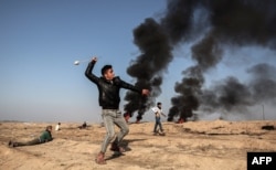 A Palestinian demonstrator swings a slingshot during clashes with Israeli forces near the border with Israel in the southern Gaza strip city of Khan Yunis on February 2, 2018. / AFP PHOTO / SAID KHATIB