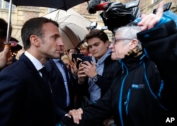 FILE - French President Emmanuel Macron argues with a resident as he arrives for a meeting at the city hall in Charleville-Mezieres, eastern France, Nov. 7, 2018.