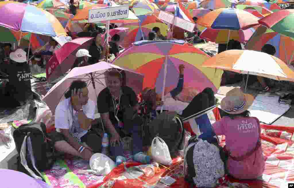 Anti-government protesters sit under beach umbrellas during a rally at the Democracy Monument, Bangkok, Thailand, Jan. 12, 2014.&nbsp;