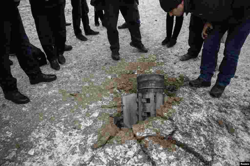 Local residents look at the remains of a rocket on a street in the town of Kramatorsk, eastern Ukraine, Feb. 10, 2015.