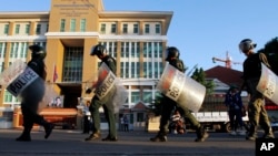 FILE - Cambodian riot police officers walk in front of Phnom Penh Municipality Court in Phnom Penh, Cambodia, May 30, 2014, after the court convicted almost two dozen factory workers and rights activists for instigating violence. The European Union is threatening to withdraw crucial trade preferences if Cambodian Prime Minister Hun Sen does not reverse a prolonged political crackdown.