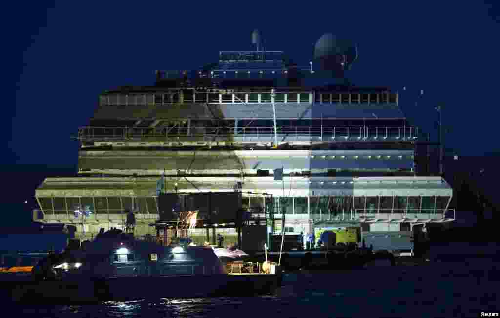 The damaged side of the capsized cruise liner Costa Concordia is visible after the ship was righted outside Giglio harbor, Italy, Sept. 17, 2013. 