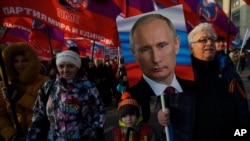 Pro-government activists with Russian flags carry a portrait of President Vladimir Putin as they march through downtown Moscow to mark People’s Unity Day, Nov. 4, 2014.