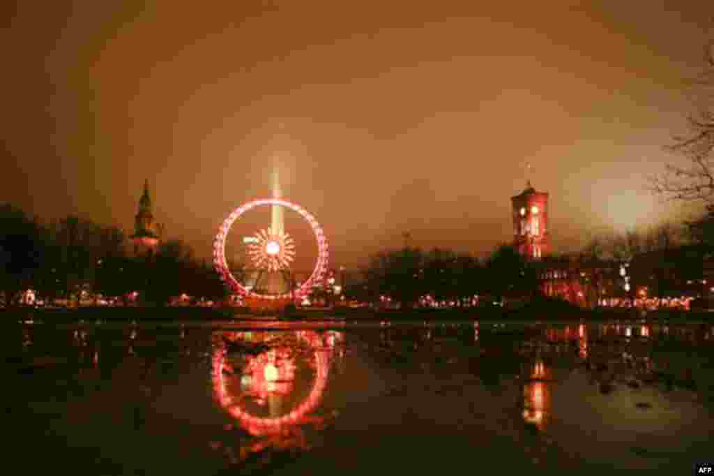 The ferris wheel at the Christmas market on the Alexanderplatz is reflected in a puddle at rainy and foggy weather in Berlin on Monday, Nov. 22, 2010. The Christmas markets in Berlin open on Monday for the Christmas season. (AP Photo/Markus Schreiber)