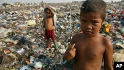 Child scavengers pose with their metal hooks used to rummage garbage amidst a mountain of trash in a Manila dumpsite, August 20, 2002.