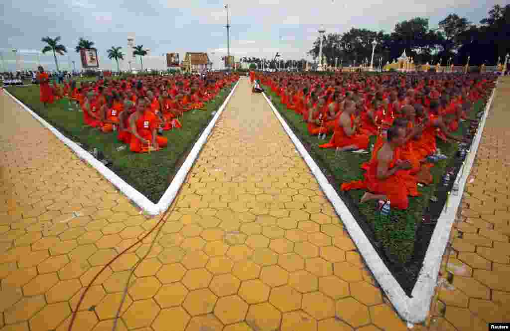 Buddhist monks sit on the grass as they pray in front of the Royal Palace during a ceremony in Phnom Penh, Cambodia. A three-day royal procession to take the remains of late Cambodian King Norodom Sihanouk from the cremation site to the Royal Palace began on July 10.