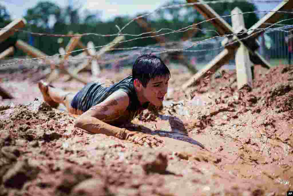 A boy crawls through mud at the inaugural Battlefrog Obstacle Course Race Series held at Georgia International Horse Park, in Conyers, Georgia, May 31, 2014.