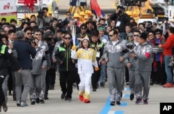 First torch bearer, South Korean figure skater You Young, center, runs as she holds an Olympic torch during the Olympic Torch Relay at Incheon Bridge in Incheon, South Korea, Wednesday, Nov. 1, 2017.