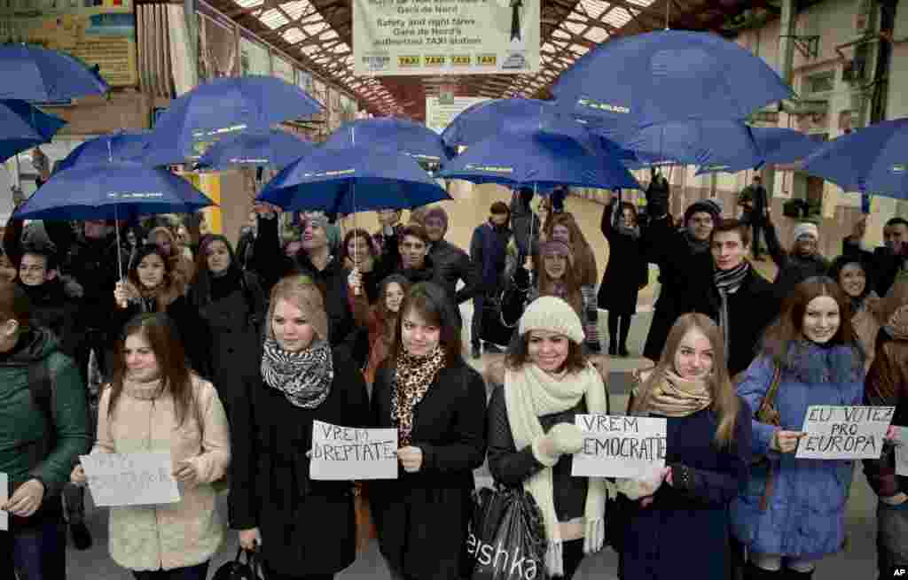Moldovan students hold signs reading " I vote pro-Europe, " " We want democracy" and " We want justice" during a flash mob of students traveling to the Romanian capital to vote, at the main railway station, Gara de Nord, in Bucharest, Romania, Nov. 30, 2014.