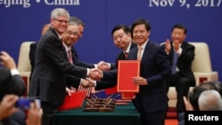 Business leaders shake hands during signing ceremony attended by U.S. President Donald Trump and China's President Xi Jinping at the Great Hall of the People in Beijing, Nov. 9, 2017.