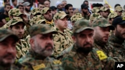 FILE - Hezbollah fighters listen to Hezbollah leader Sheik Hassan Nasrallah, as he speaks via a video link during a rally to mark the Hezbollah martyr day, in the southern suburb of Beirut, Lebanon.