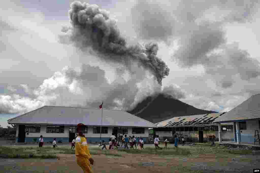 Children play at an elementary school as the Mount Sinabung volcano spews smoke in Karo, Indonesia.