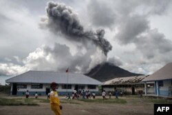 Children play at an elementary school as the Mount Sinabung volcano spews smoke in Karo on November 13, 2017.