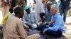 Le secrétaire général adjoint aux affaires humanitaires des Nations Unies (OCHA) et le Coordonnateur des secours d'urgence Mark Lowcock, à gauche, discute avec des hommes dans un camp des Nations Unies pour les réfugiés et les personnes déplacées à NGag