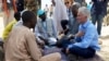 Le secrétaire général adjoint aux affaires humanitaires des Nations Unies (OCHA) et le Coordonnateur des secours d'urgence Mark Lowcock, à gauche, discute avec des hommes dans un camp des Nations Unies pour les réfugiés et les personnes déplacées à NGag