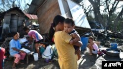 Des habitants se rassemblent près de leur maison détruite à Carcar, aux Philippines, le 18 décembre 2021, quelques jours après la chute du typhon Rai.