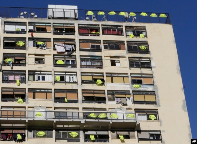 Yellow vests hang on the rooftop and at windows of an apartment building, Dec. 7, 2018, in Marseille, southern France.