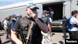 People surround a refrigerated rail car with remains of victims of downed Malaysia Airlines Flight MH17 at a rail station in Torez, Ukraine, as OSCE monitors and forensic investigators arrive Julyl 21, 2014.