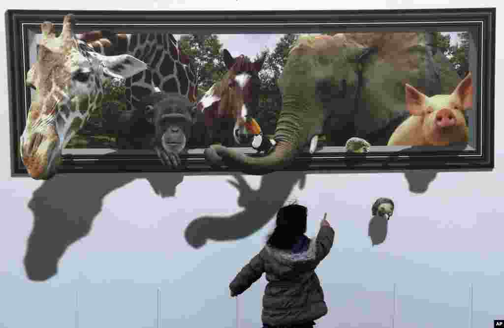 A girl looks at a 3D picture of animals drawn at a construction site of the archery venue for the Tokyo 2020 Summer Olympics in Tokyo, Japan.