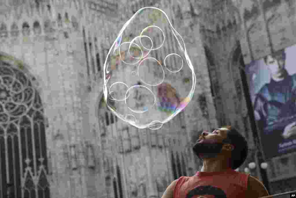 A street artist performs with soap bubbles in front of the Duomo gothic cathedral, in Milan, Italy.