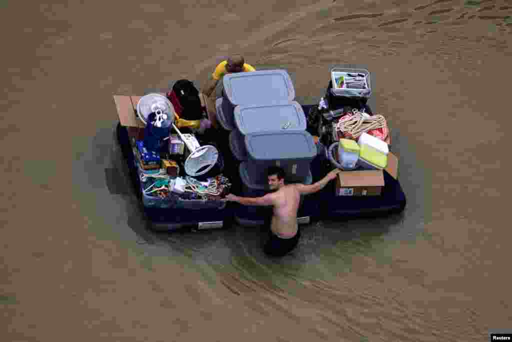 Residents wade with their belongings through flood waters brought by Tropical Storm Harvey in Northwest Houston, Texas, Aug. 30, 2017.