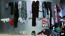 A kid sleeps under laundry at the migrant and refugee registration camp in Moria village on the northeastern Greek island of Lesbos, Nov. 12, 2015.