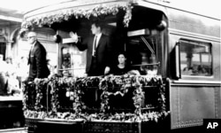 FILE - Sen. Edward M. Kennedy waves from the rear platform of the observation car bearing the remains of his slain brother, Sen. Robert F. Kennedy, as the funeral train passed through North Philadelphia Station, June 8, 1968.