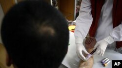 A man has a sample of blood taken by a nurse for testing at the HIV/AIDS ward of Beijing YouAn Hospital. The number of new HIV/AIDS cases in China is soaring, with rates of infections among college students and older men rising. The Chinese Center for Dis
