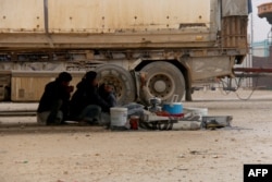 FILE - Displaced Syrians fleeing areas in the northern embattled province of Aleppo, sit under a truck at the Bab al-Salama camp, set up outside the Syrian city of Azaz on Syria's northern border with Turkey, Feb. 12, 2016.
