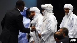 Malian Foreign Minister Abdoulaye Diop, left, shakes hands with representatives of Malian armed rebel groups at the end of a peace agreement ceremony in the Algerian capital Algiers, March 1, 2015.