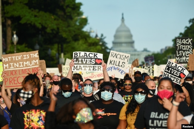 Protesters hold placards during a demonstration against the death of George Floyd while in Minneapolis police custody, in Washington, U.S., June 13, 2020.