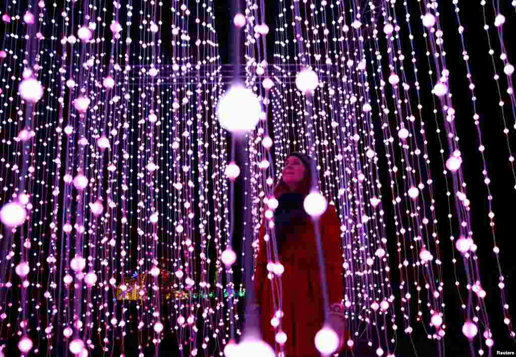 A woman poses among illuminations at a photo-call for the Christmas at Kew Festival in London, Britain.